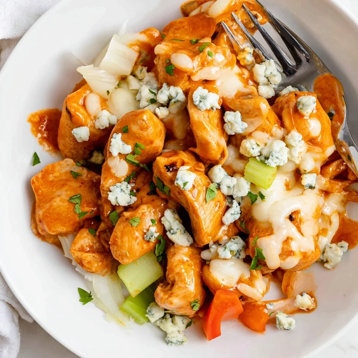 Colorful Keto Buffalo Chicken Skillet topped with crumbled blue cheese and celery.