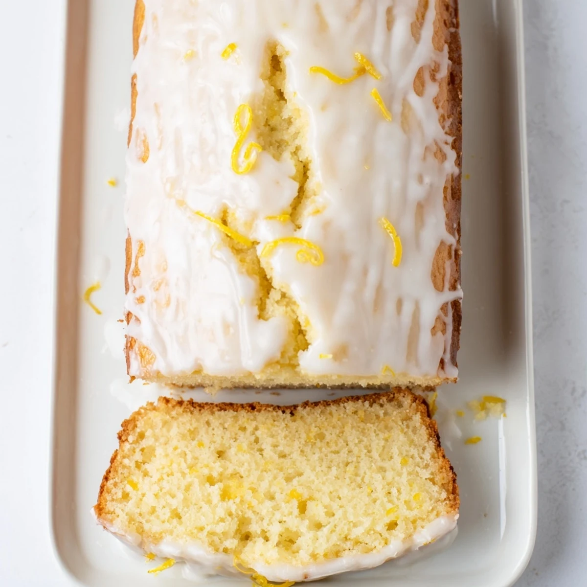 Thick slice of moist Greek yogurt lemon loaf served on white plate with powdered sugar dusting