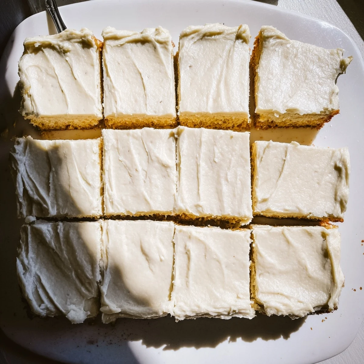 Thick banana bread brownies topped with swirls of nutty brown butter frosting on a white plate