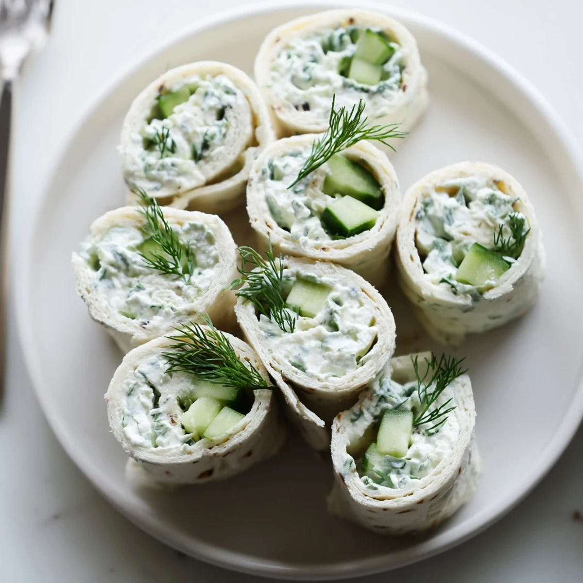 Cucumber And Dill Pinwheels arranged on platter, chilled, creamy filling visible