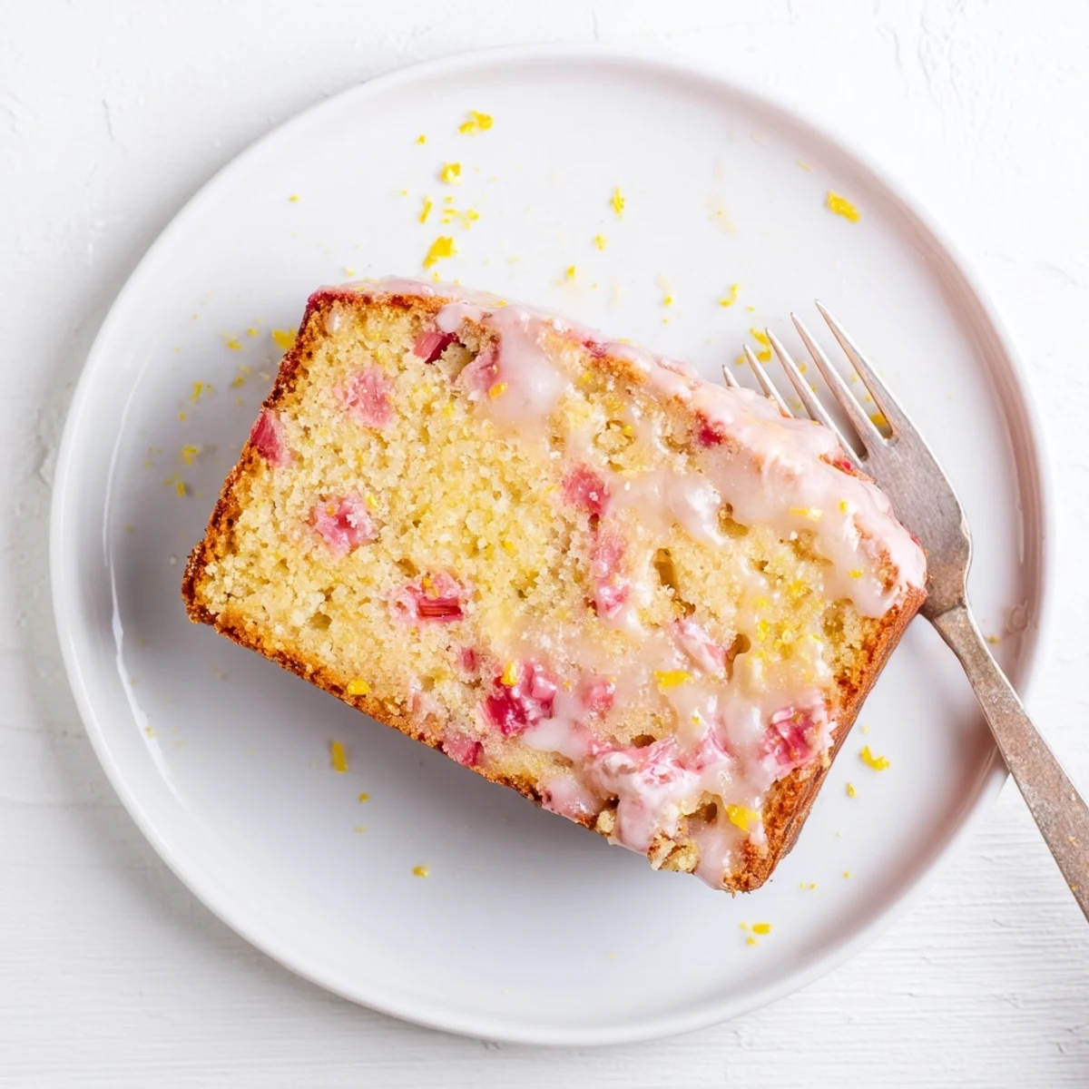 Freshly baked rhubarb lemon drizzle cake topped with powdered sugar and lemon zest garnish