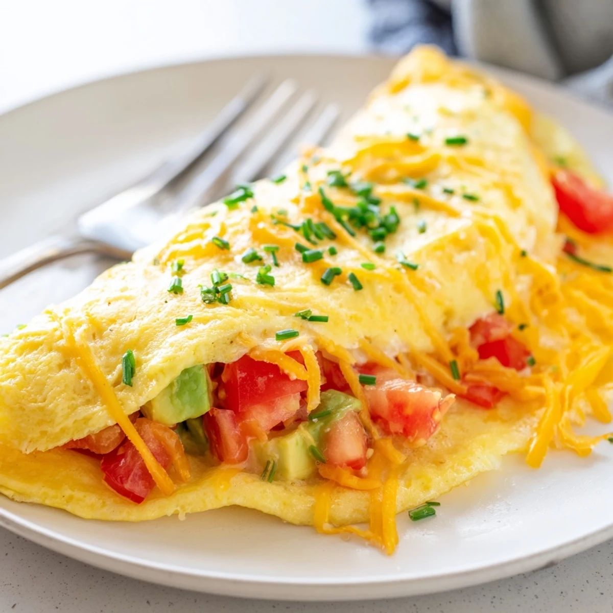 Creamy avocado cheesy tomato omelette garnished with fresh chives and served warm