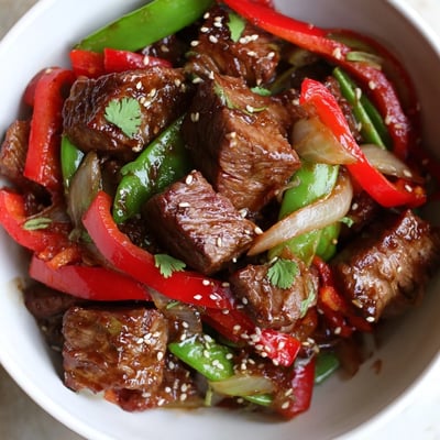 Juicy pan-seared Asian-inspired cube steak topped with sesame seeds over colorful bell peppers