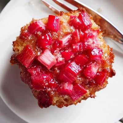 Warm upside down rhubarb muffins flipped to reveal glossy, sweet-tart ruby rhubarb topping